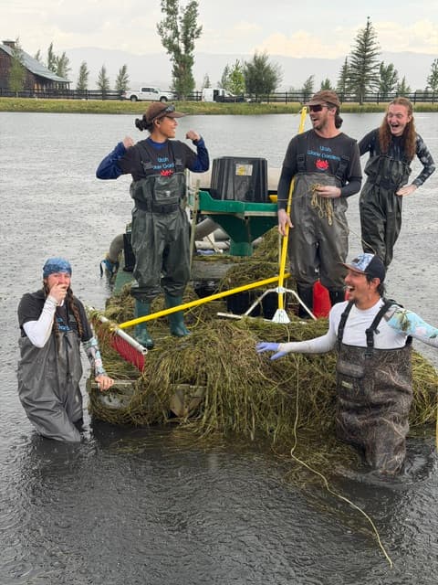 Five Utah Water Gardens team members smiling together during aquatic weed removal